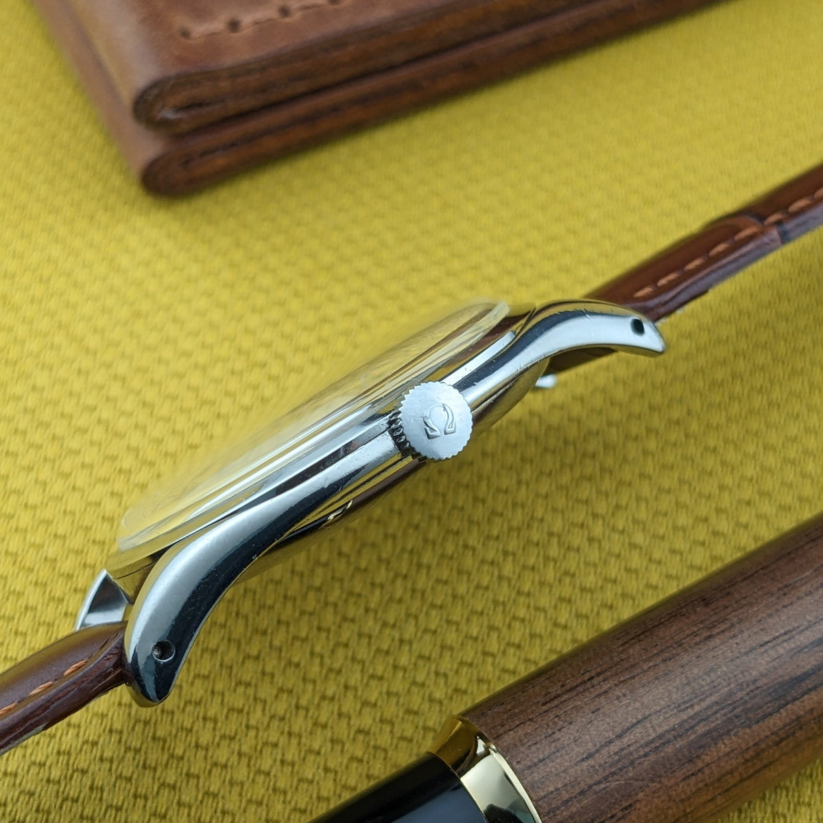 Seitenprofil der Omega Jumbo Referenz 2505-10 zeigt das gebogene Gehäuse, die Krone mit Omega-Symbol und das befestigte Lederarmband.