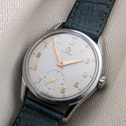 Angled close-up of the OMEGA Classic 2639-11 silver dial with gold numerals, subsidiary seconds, polished case, and green strap.