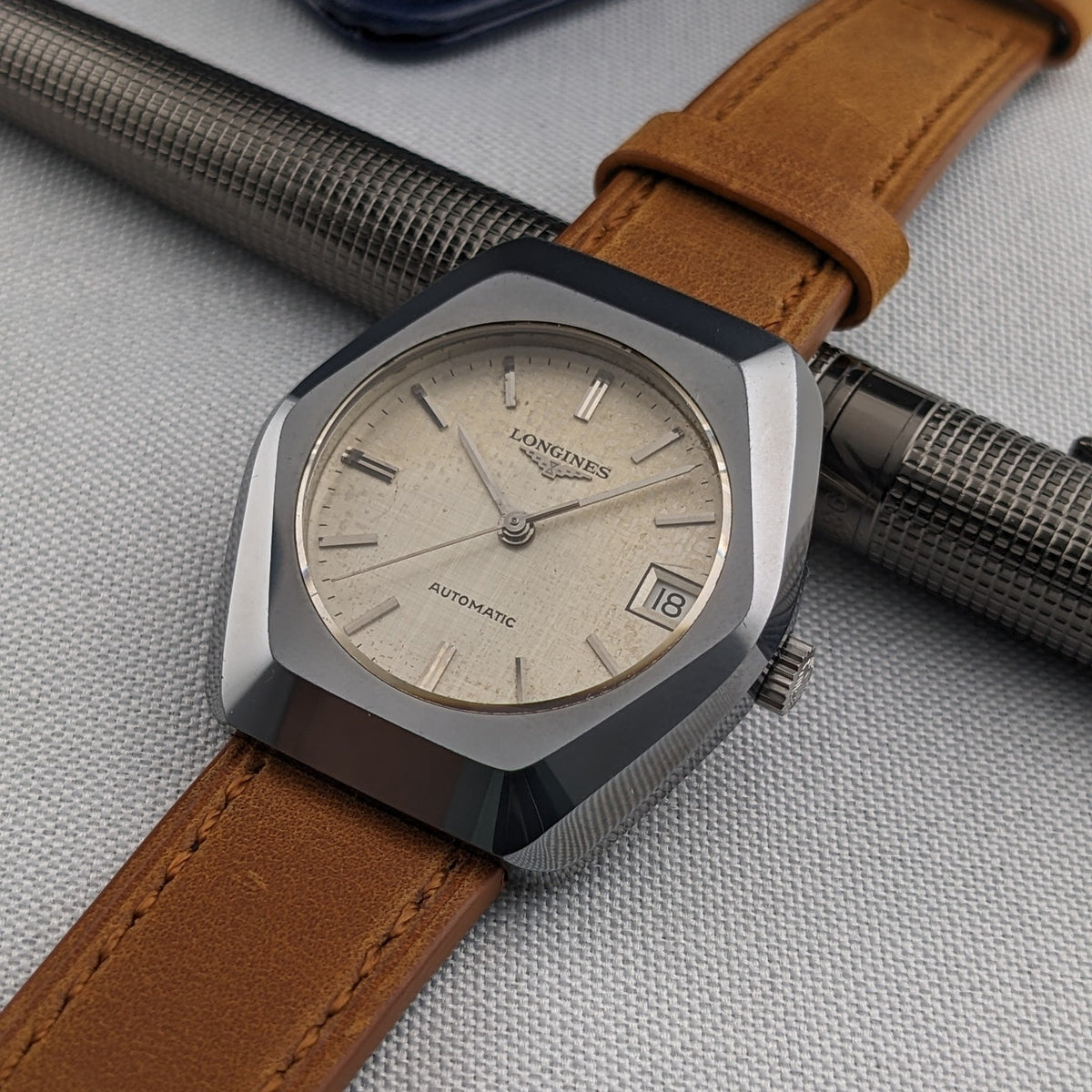 Three-quarter view of the LONGINES Automatic reference 3042-633 with cream dial, date showing 18, faceted case and brown strap.
