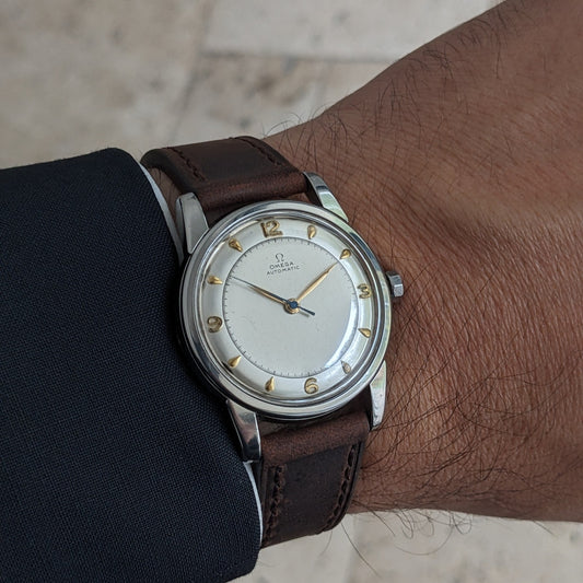 Omega Automatic Bumper reference 2767-4 SC worn on a wrist with a brown leather strap, cream dial and dark jacket sleeve.