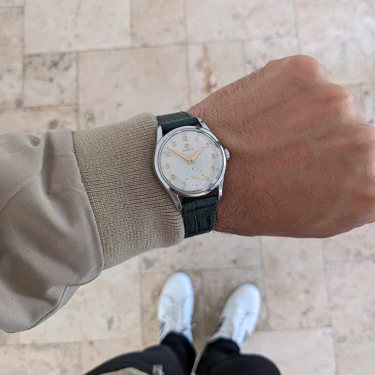 OMEGA Classic referenza 2639-11 indossato su un polso sopra un pavimento piastrellato chiaro, con cinturino verde, manica beige e scarpe visibili.