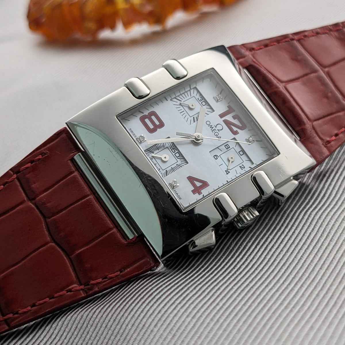 Omega Constellation Quadra 1841.73.31 presented diagonally with a white dial, red numerals, polished case, and crocodile-pattern red strap.