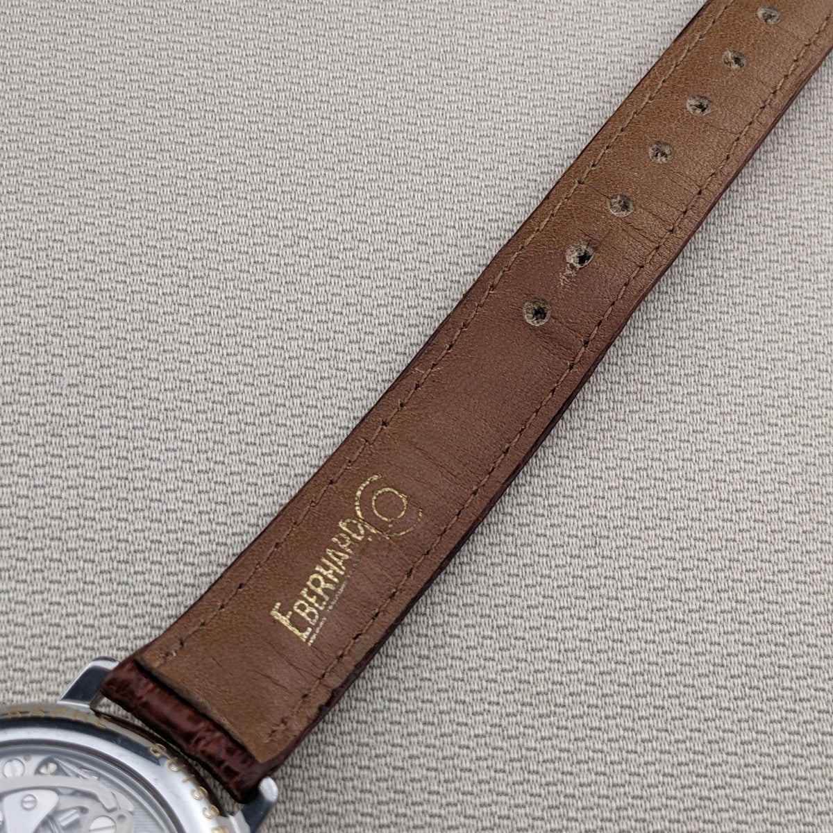 Partial rear view of the Eberhard & Co. Godron Chrono reference 32031, showing the brown leather strap, details holes and visible movement edge.