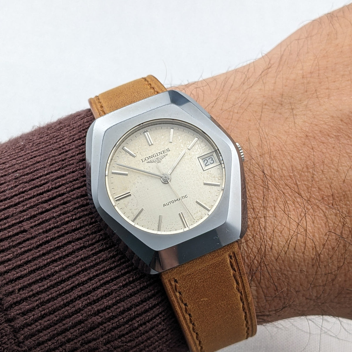 The LONGINES Automatic reference 3042-633 worn on a wrist, showing its cream dial, date window marked 23 and brown leather strap.