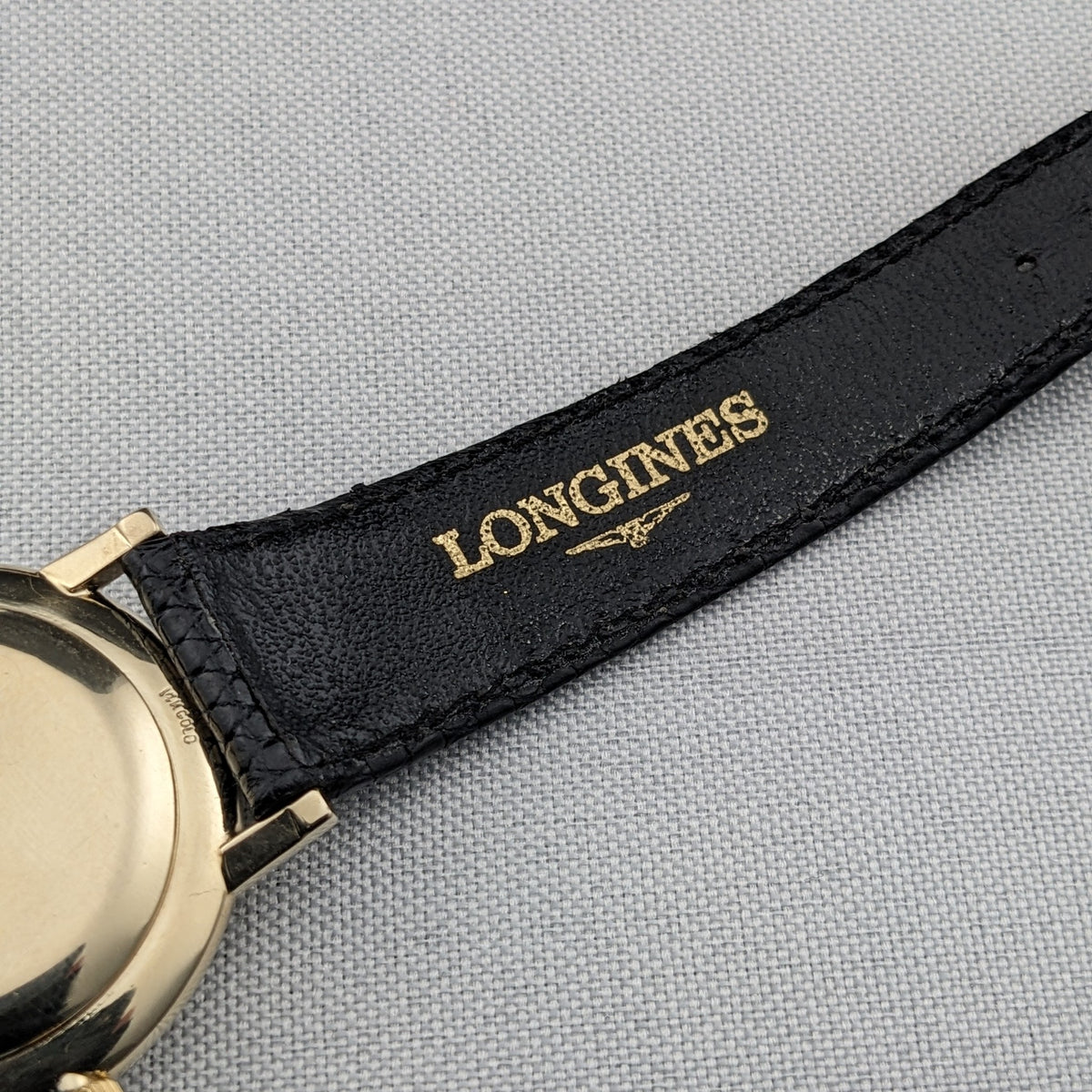 Close-up of the black strap attached to the Longines Ultra-Chron 69-556AC, with gold LONGINES lettering visible on the underside.