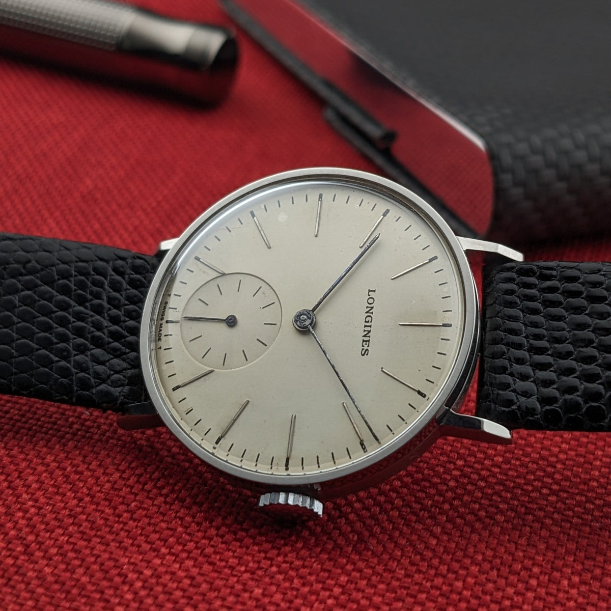 Longines Calatrava reference 20757 shown at an angle with its light dial, slim markers, small seconds, crown, and textured black strap.