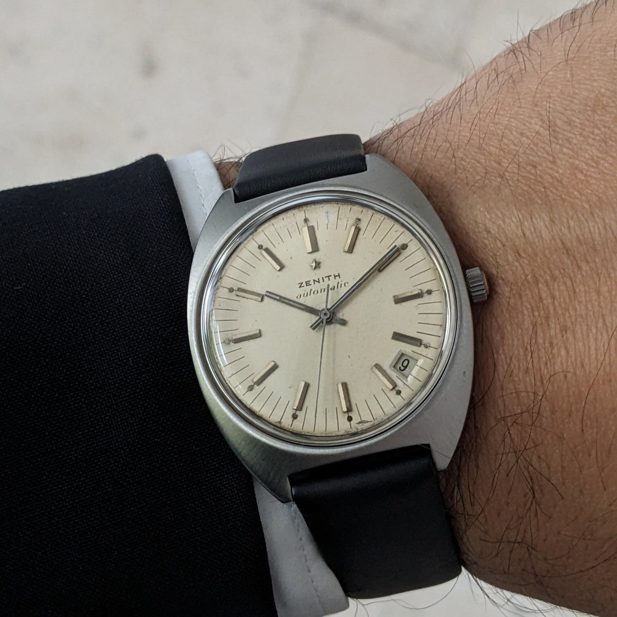 Close-up of the Zenith Automatic reference GR 720001 worn on the wrist, showing the light dial, date window, crown, and black strap.
