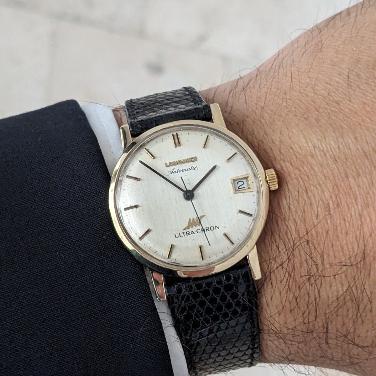 Longines Ultra-Chron reference 69-556AC worn on a wrist, showing the cream dial, date window, gold-tone case, and black strap.