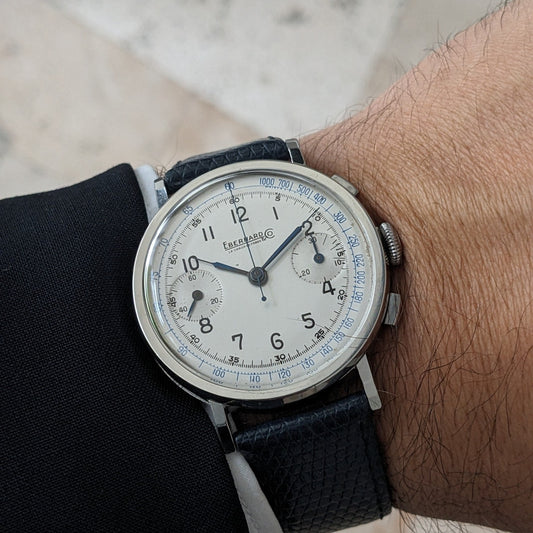 Close wrist view of the Eberhard & Co. Pre-Extra Fort showing its cream chronograph dial, blue scales, crown and dark blue strap.