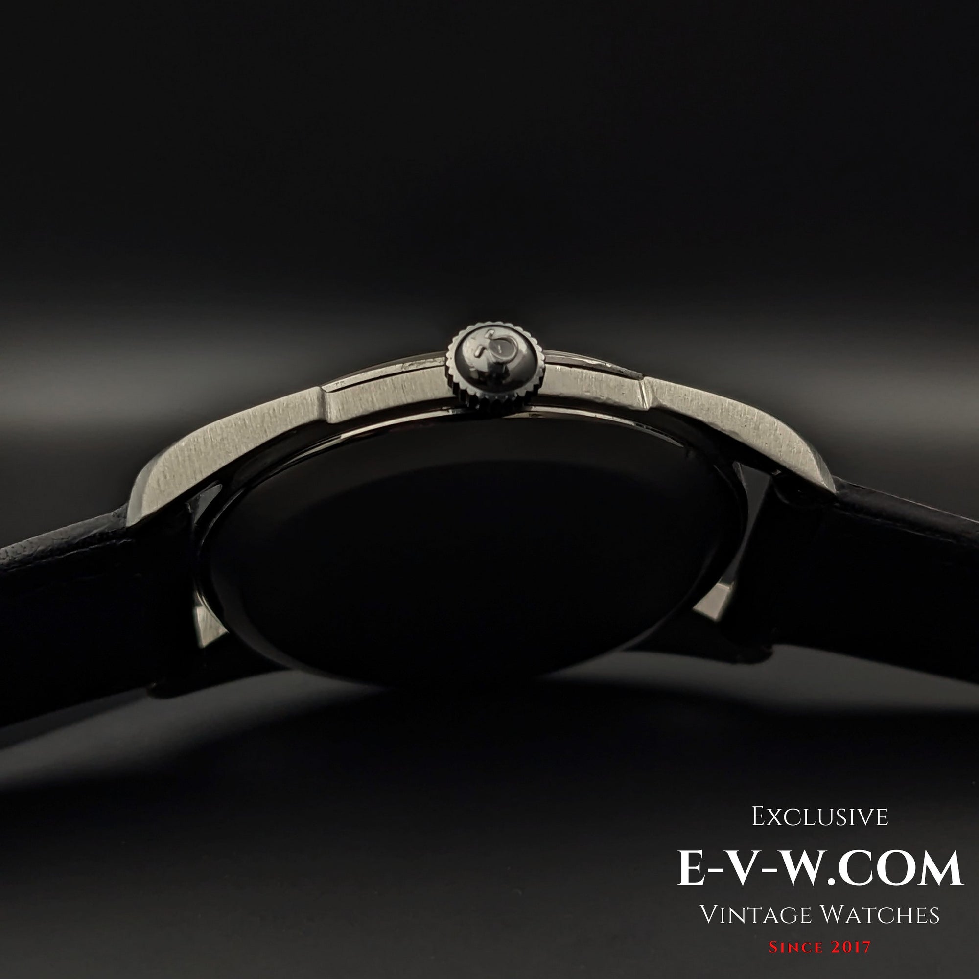 Side profile of Omega CK 2900 Vintage 1956 watch, highlighting the signed Omega crown and polished stainless steel case. A refined vintage watch.