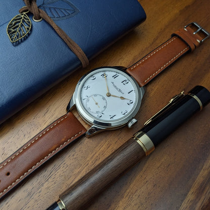 Watch with brown leather strap and blue notebook on wooden surface