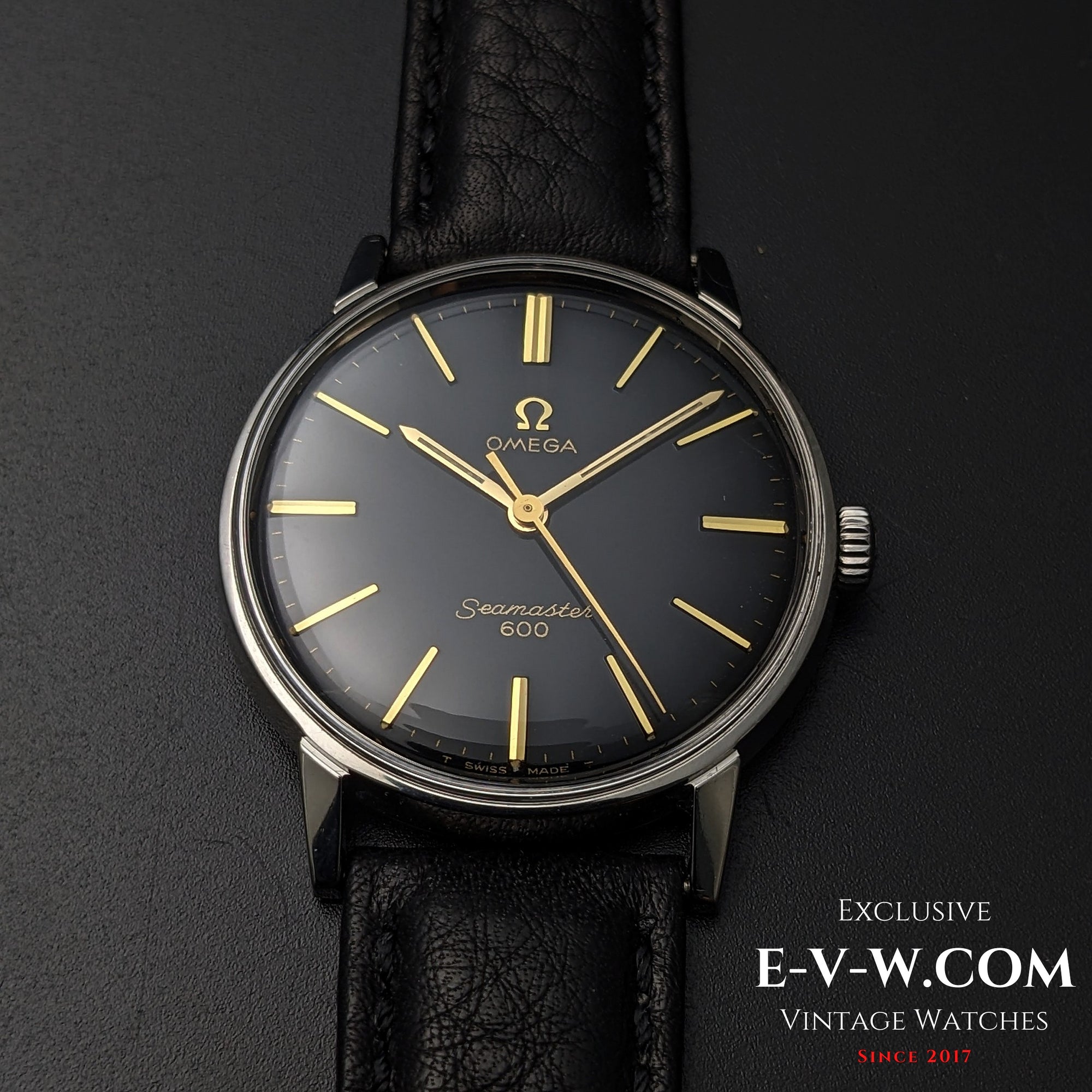 Front-facing view of Vintage Omega Seamaster 600 1966 Ref. 135011 with black dial, gold markers, and black leather strap on dark surface.