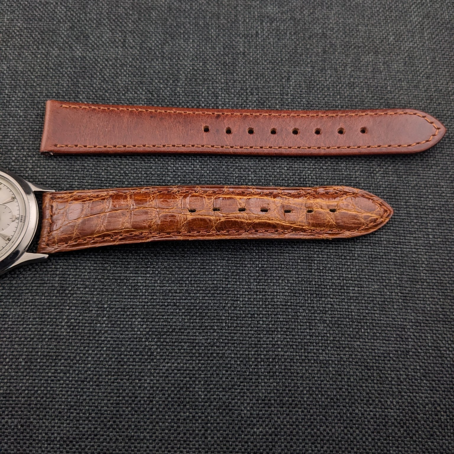 Close view of the Jaeger-LeCoultre Automatic E328 brown textured strap beside a separate plain brown strap.