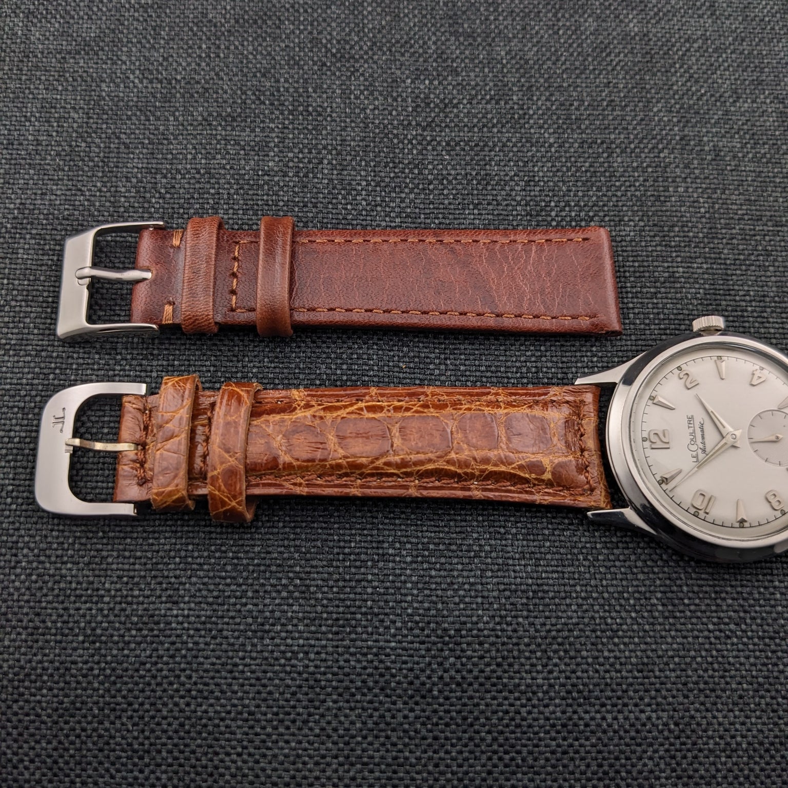 Jaeger-LeCoultre Automatic E328 appears at right beside two brown straps, each shown with a metal buckle.