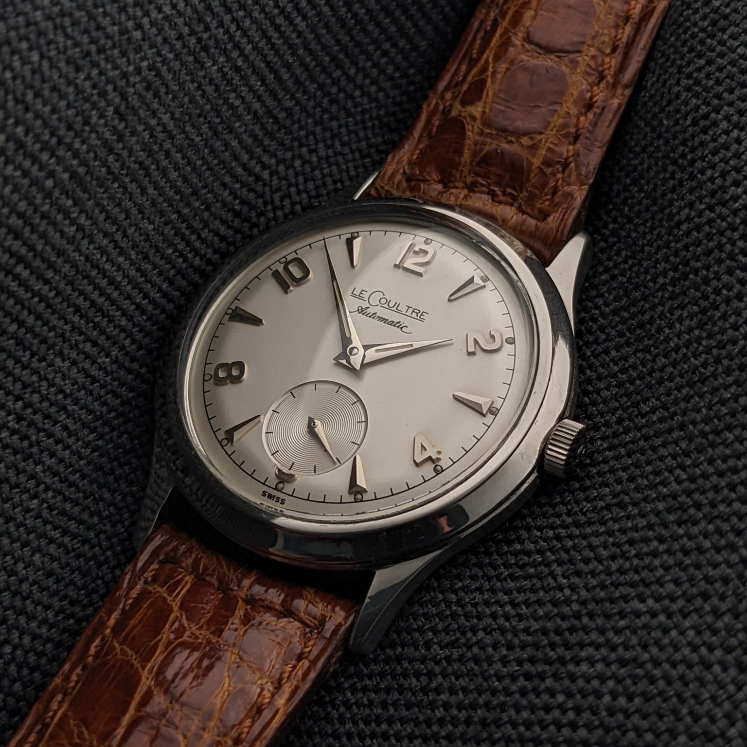 Close-up of the Jaeger-LeCoultre Automatic E328 silver-tone dial, applied numerals, small seconds subdial, and brown strap.
